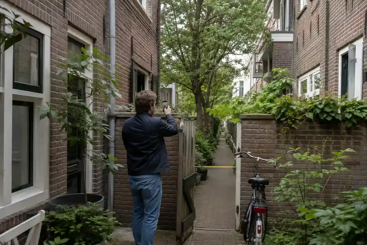 Bewoner fotografeert de smalle toegang naar een Amsterdamse binnentuin